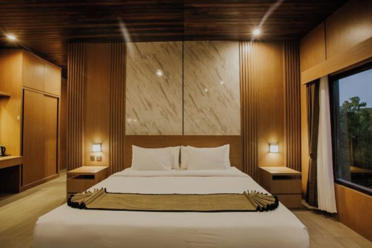 A hotel room with a large bed, wooden paneling, marble accents, and bedside lamps.