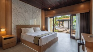 Quarto moderno com uma cama grande, mesas de cabeceira de madeira, uma escrivaninha e vista para o pátio externo.