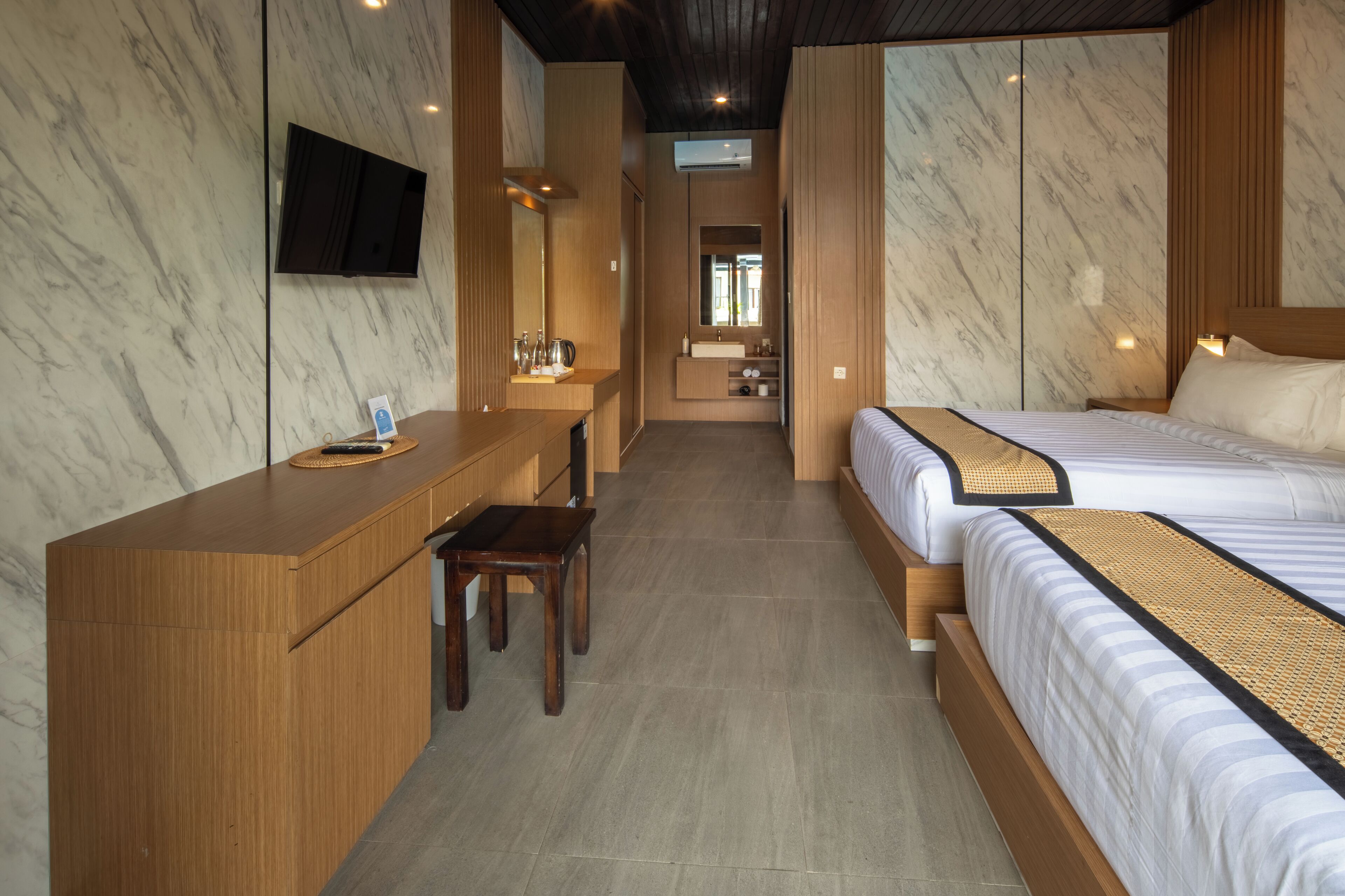 A modern hotel room with a wooden desk, a bed with striped bedding, and a large mirror.