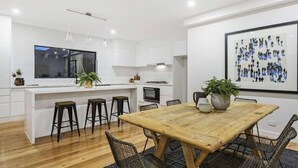 Una cocina moderna con armarios blancos, una mesa de comedor de madera y taburetes negros.