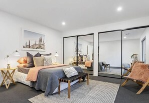 Relax in this serene bedroom with a large bed, bedside tables, and a comfortable bench.