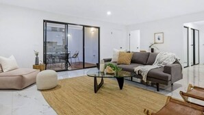 Una sala moderna con una mesa de centro de vidrio, un sofá y una silla.