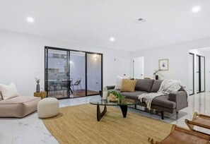 Relax in this stylish living space, featuring a sofa, coffee table, and comfortable seating area with a view to the outdoor dining space.