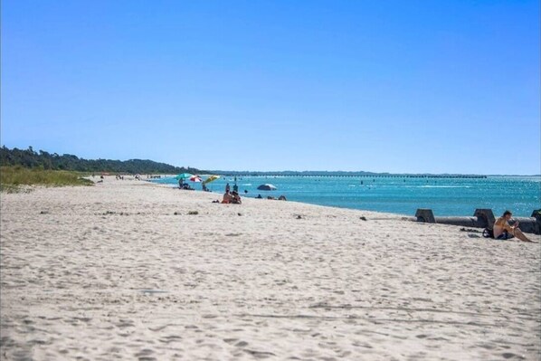Enjoy a serene beach experience with a wide sandy shore and calm sea.