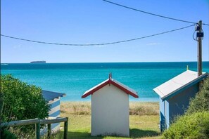 Enjoy breathtaking ocean views from this coastal retreat, featuring a charming white building and a larger structure amidst lush surroundings.