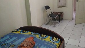 Un dormitorio con una cama, una silla, una mesita y una ventana con cortina.