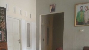 Un salón amplio con suelo de baldosas, un mueble de madera y un sillón de cuero rojo.