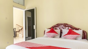 Een hotelkamer met een bed, een houten hoofdbord en een deken met een rood-wit patroon.