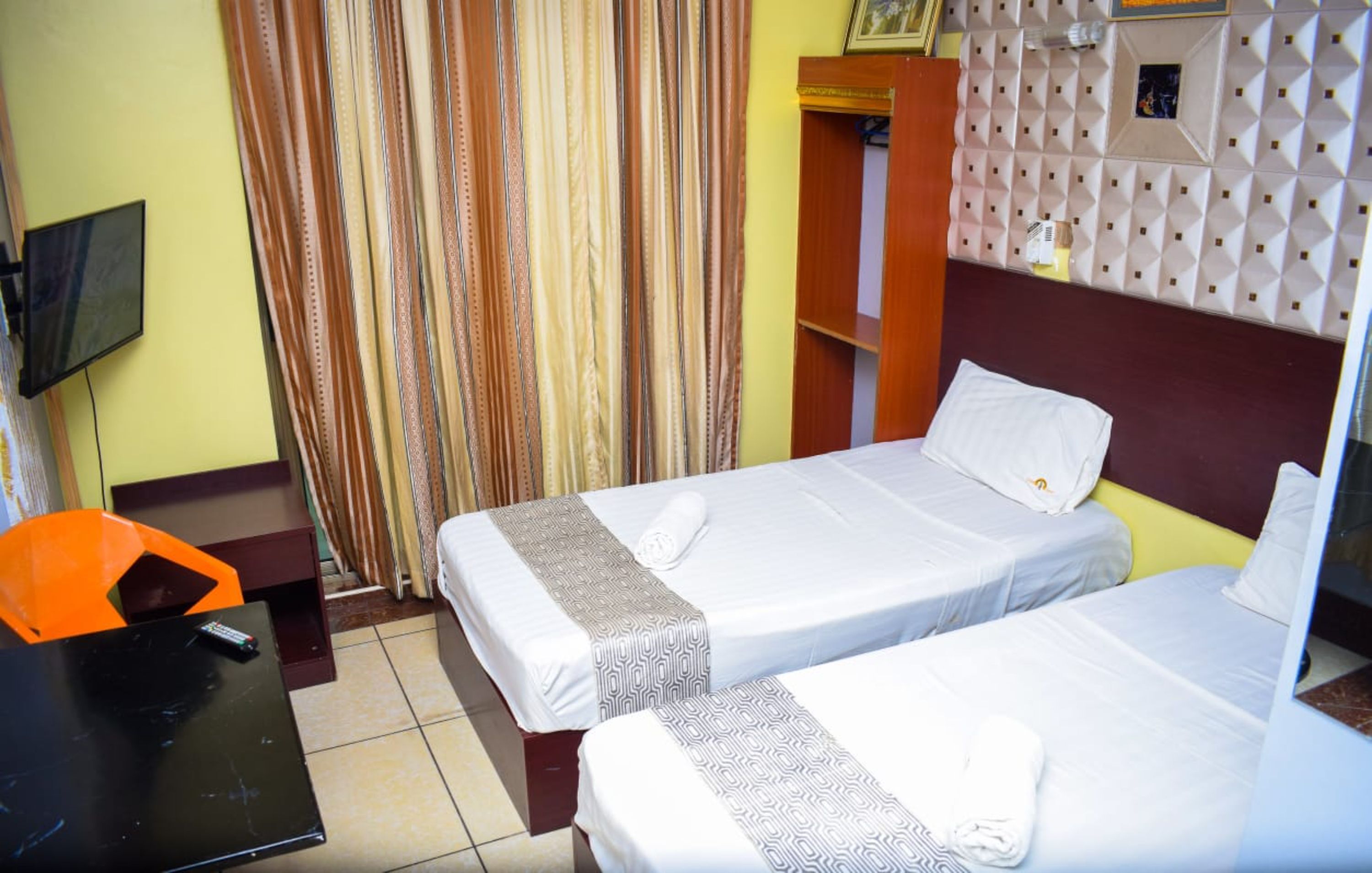 A hotel room with two beds, a TV, and a small table.