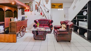 Een ruime woonkamer met een rode leren bank, een houten salontafel en een vintage kar.