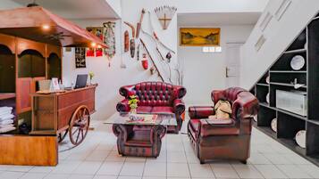 A spacious living room with a red leather sofa, a wooden coffee table, and a vintage cart.