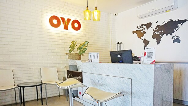 A reception area with a marble counter, two bar stools, a world map on the wall, and a sign that reads "OYO". - OYO 91455 New Hotelo (Jakarta)