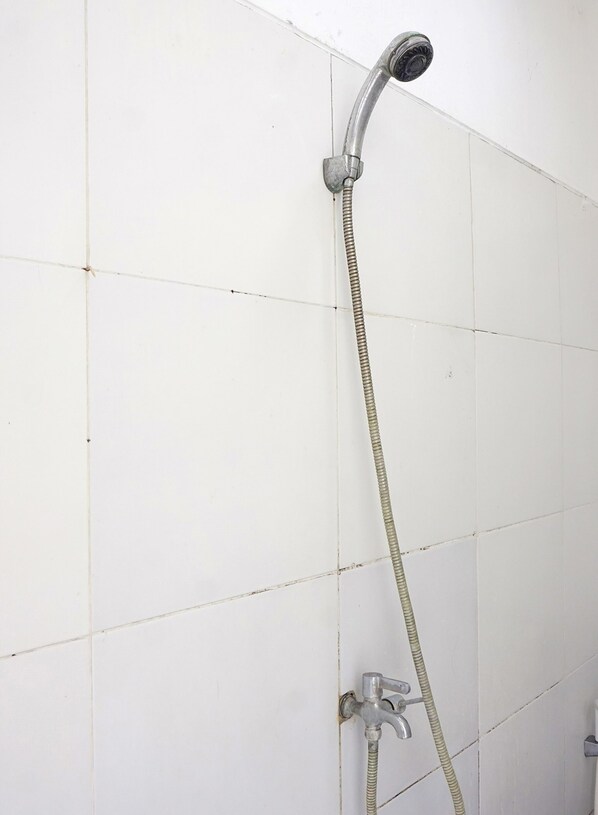 A shower with a flexible hose and a handheld showerhead mounted on a wall with white tiles.