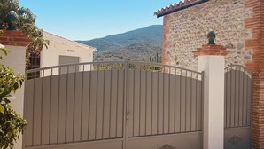 Un ingresso chiuso da un cancello in metallo, con un muro di pietra, che conduce a un edificio con tetto in tegole.