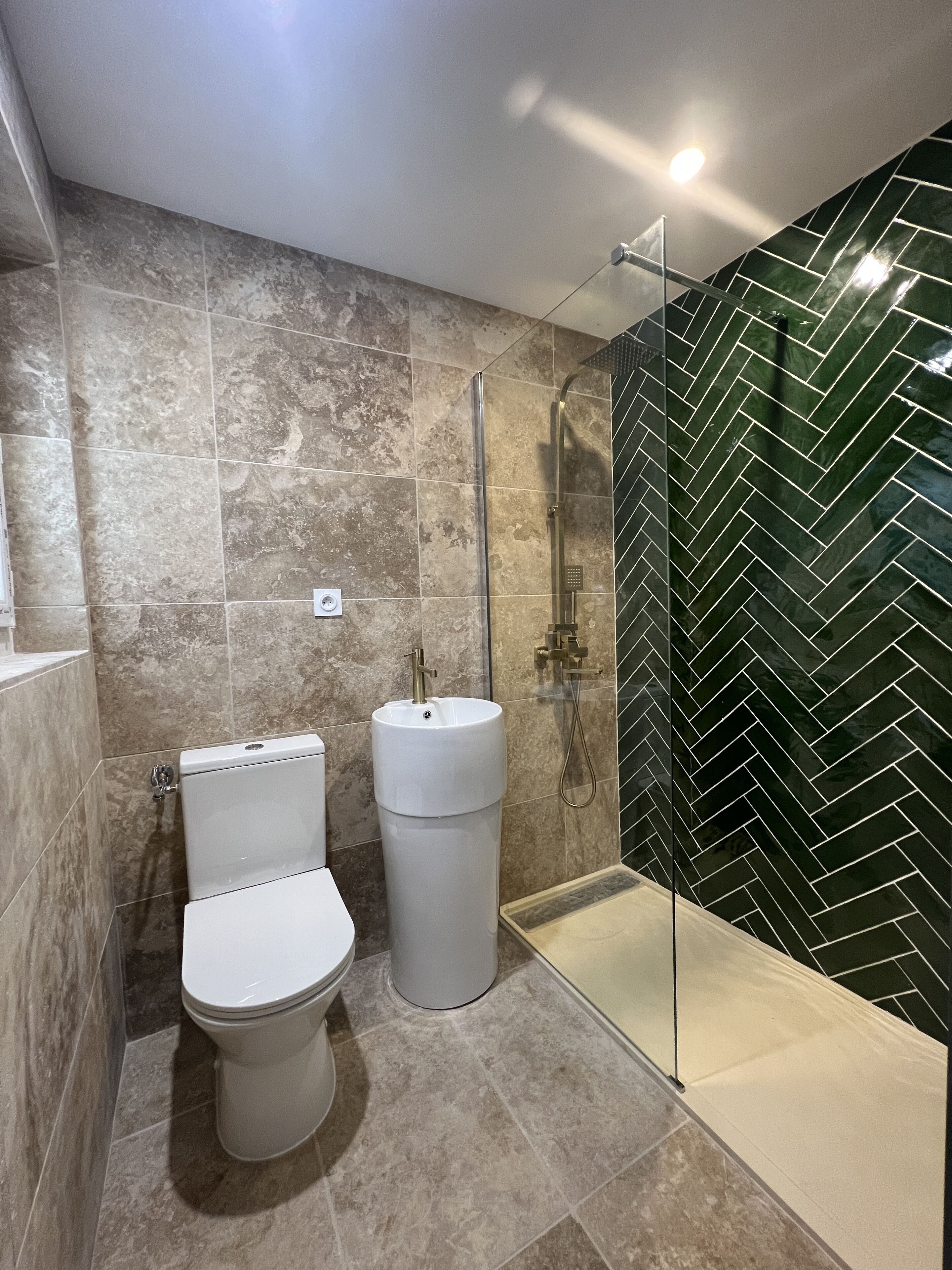 Une salle de bain moderne équipée de toilettes, d’un lavabo et d’une douche à parois de verre.