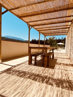 Une terrasse extérieure avec des bancs en bois et un toit de chaume.