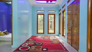 A hallway with a red patterned rug, wooden doors, and a blue wall. - OYO Homes 90916 Eco Tourism Geopark Rajamandala Homestay Syariah (Rajamandala Kulon)