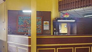 Zona de recepción con un mostrador de madera, obras de arte enmarcadas en las paredes y un reloj en la pared.