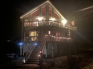 A two-story building with a balcony, a staircase, and a flag. - Gorgeous 6BR house, Wild Horses, stunning views! Private parking. 4WD required. (Corolla)