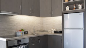 Una cocina moderna con armarios oscuros, un refrigerador de acero inoxidable y un salpicadero de azulejos.