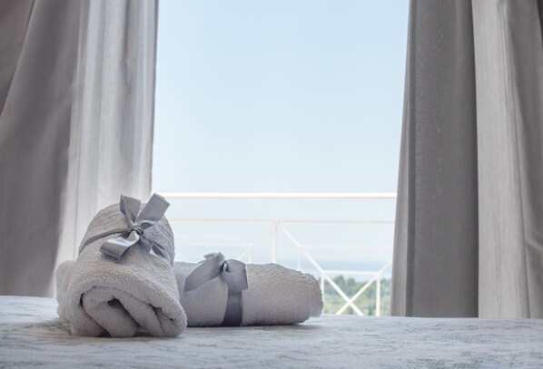 A neatly folded towel with a bow on a balcony with a railing and a view of the sky.
