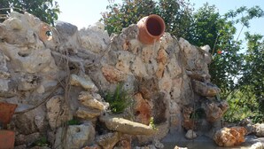 Un espacio al aire libre con rocas, una maceta de barro y una pequeña fuente de agua.
