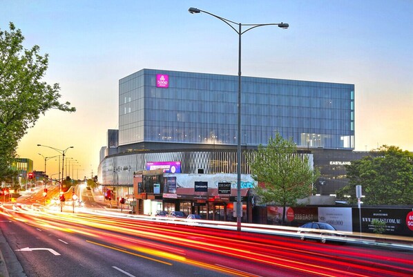 A modern building with a glass facade, street lights, and a clear sky.