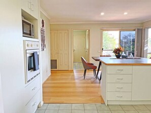 A kitchen with a microwave, oven, and a dining area with a chair and table.