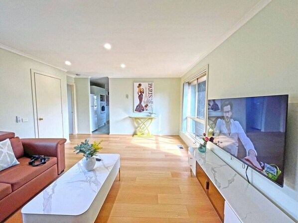 A modern living room with a sofa, coffee table, and a flat-screen TV mounted on the wall.