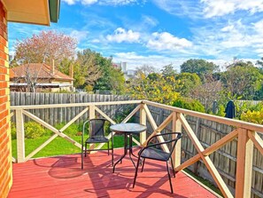 A deck with a red floor, two chairs, and a small table.