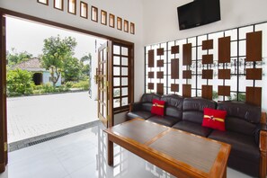 A modern living room with a sofa, a coffee table, and a decorative wall panel. - Hotel O Forrest’inn (Kediri)