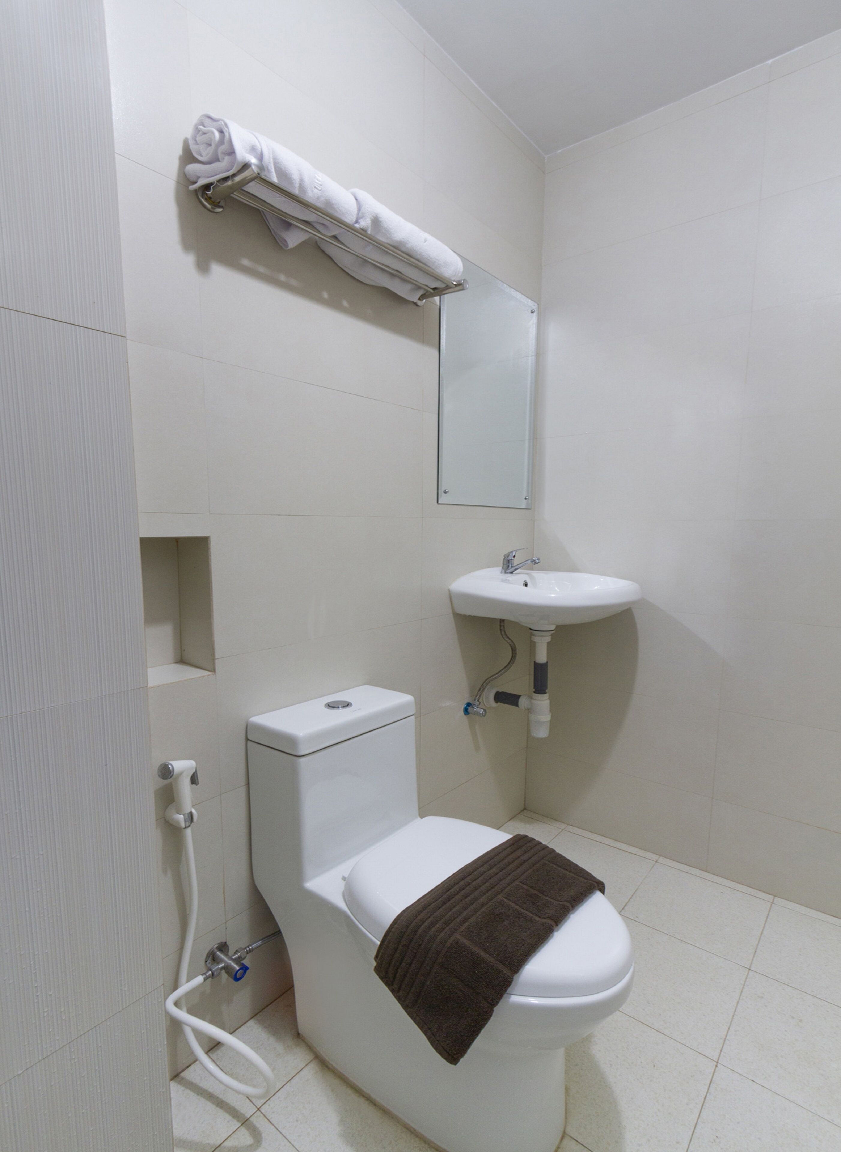 A small, clean bathroom with a toilet, sink, and towel rack.