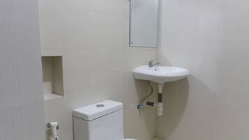Un baño pequeño y limpio con inodoro, lavamanos y toallero.