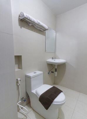 A small, clean bathroom with a toilet, sink, and towel rack. - Hotel O Forrest’inn (Kediri)