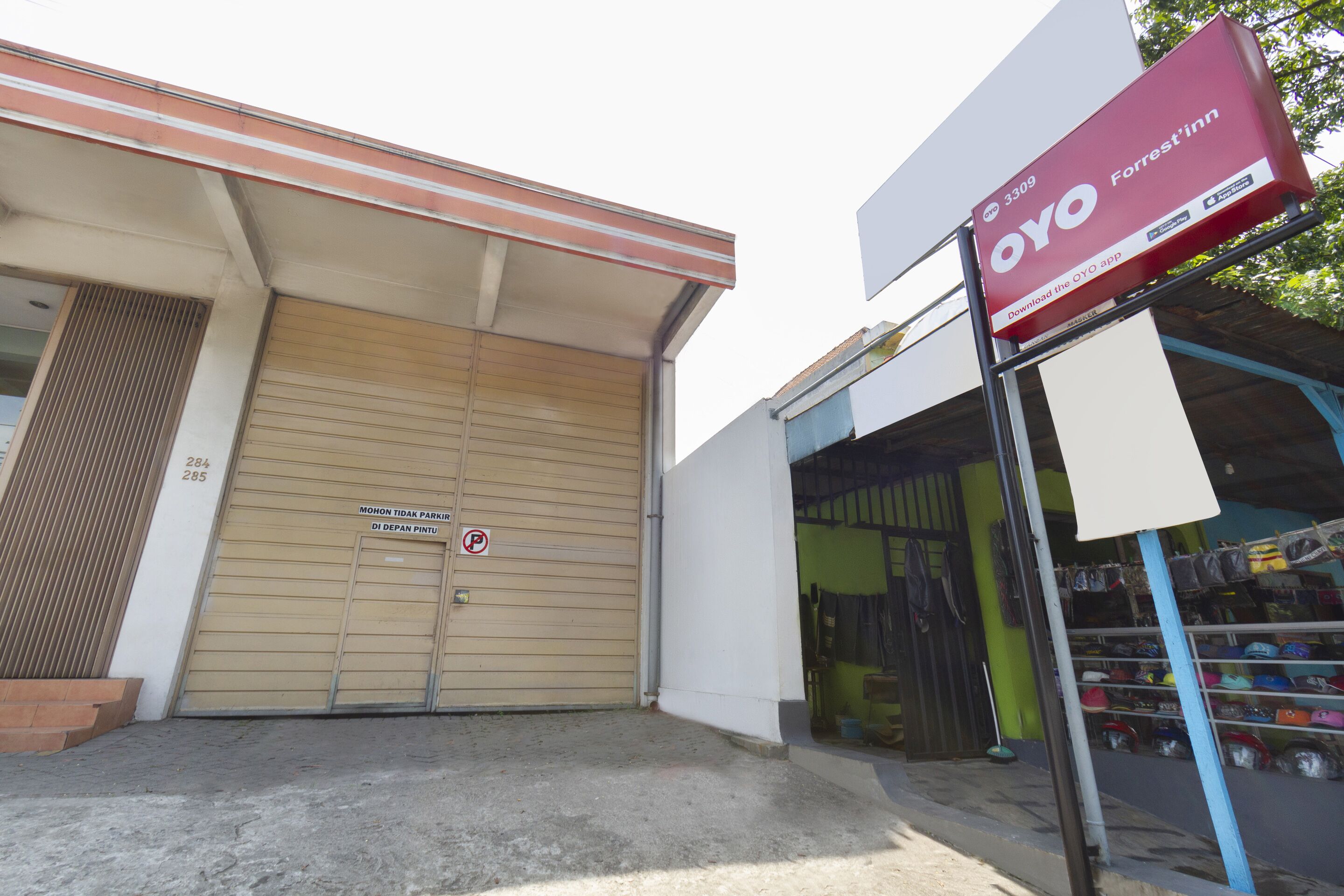 A storefront with a closed garage door, a signboard for OYO Forrest'in, and a display of various items outside.