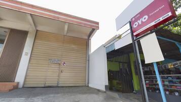 A storefront with a closed garage door, a signboard for OYO Forrest'in, and a display of various items outside.