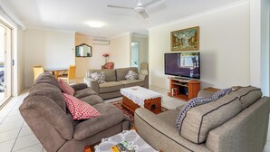 Una sala de estar con sofás, televisor y ventilador de techo.