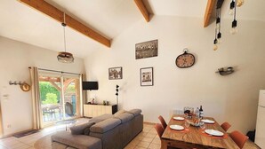 Un salon moderne avec un canapé, une table à manger et des chaises. On y trouve également un téléviseur, une horloge et des tableaux encadrés accrochés aux murs.