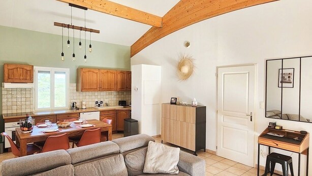 Une cuisine moderne avec des meubles en bois, un coin repas comprenant une table et des chaises, un canapé et un bureau avec une chaise.