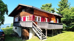Eine Holzhütte mit Balkon, Treppe und Steinfundament.