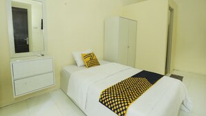 A bedroom with a bed, a wardrobe, a mirror, and a bedside table. - OYO 91635 Wisma Terace House (Jakarta)