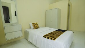 A bedroom with a bed, a wardrobe, a mirror, and a bedside table. - OYO 91635 Wisma Terace House (Jakarta)