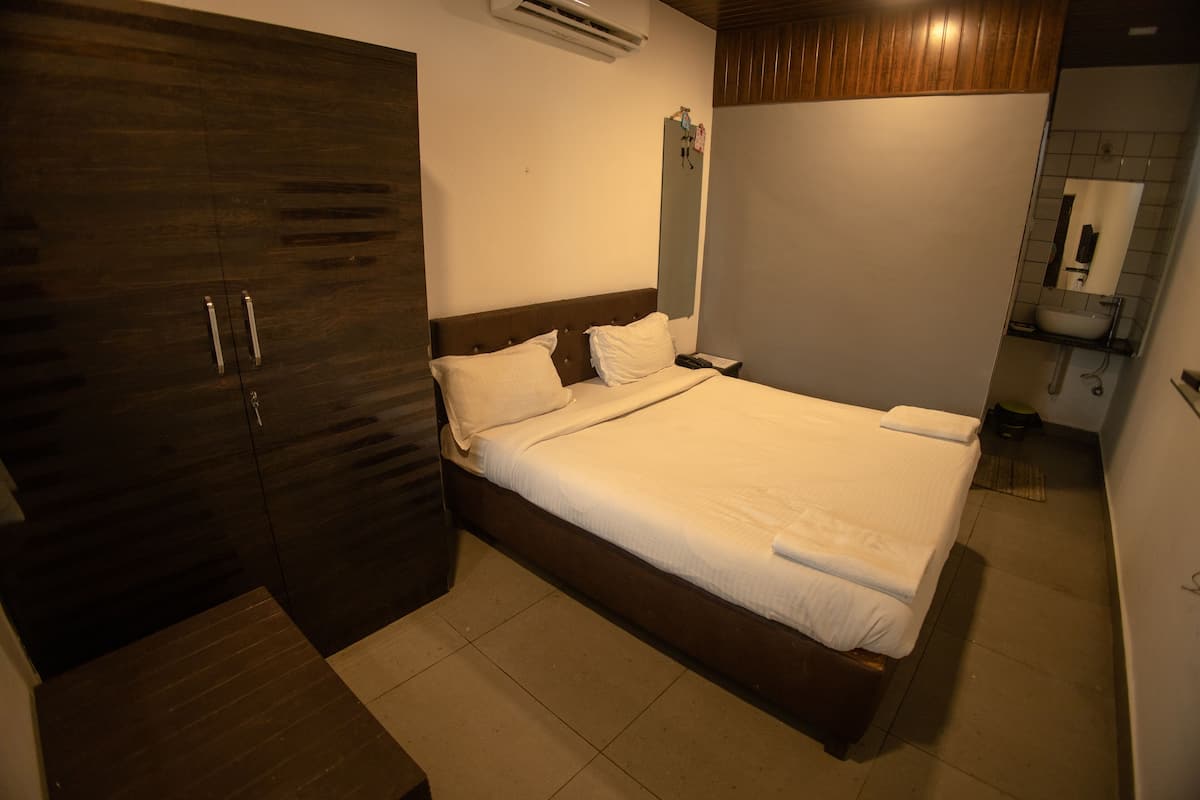 A hotel room with a large bed, a wardrobe, a mirror, and a bathroom with a sink and toilet.