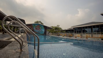 A swimming pool with a mural, metal railings, and a covered area with potted plants.