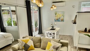 A modern living room with a beige sofa, a dining table, and a kitchen area.
