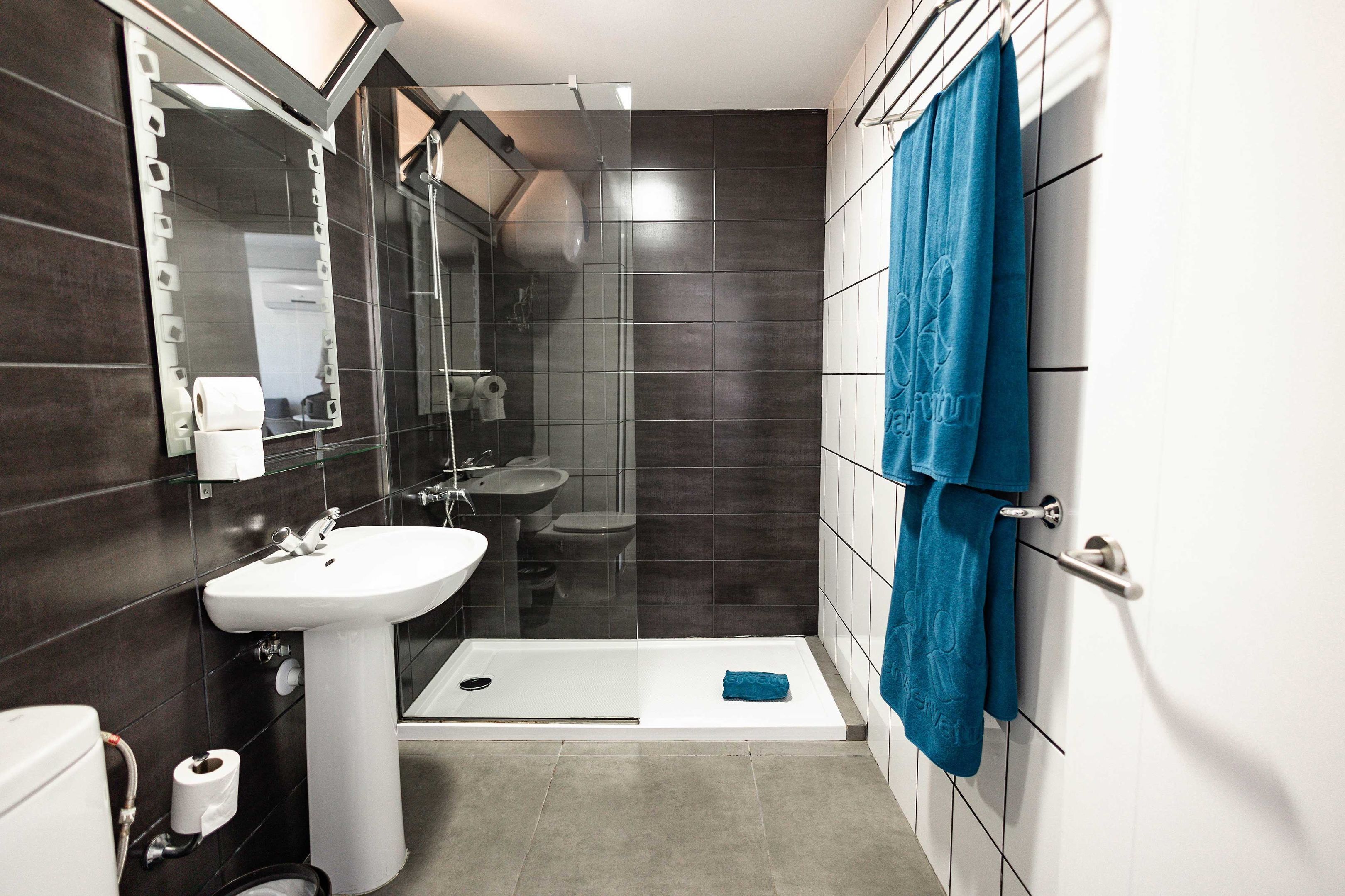 A modern bathroom with a shower, sink, and toilet.