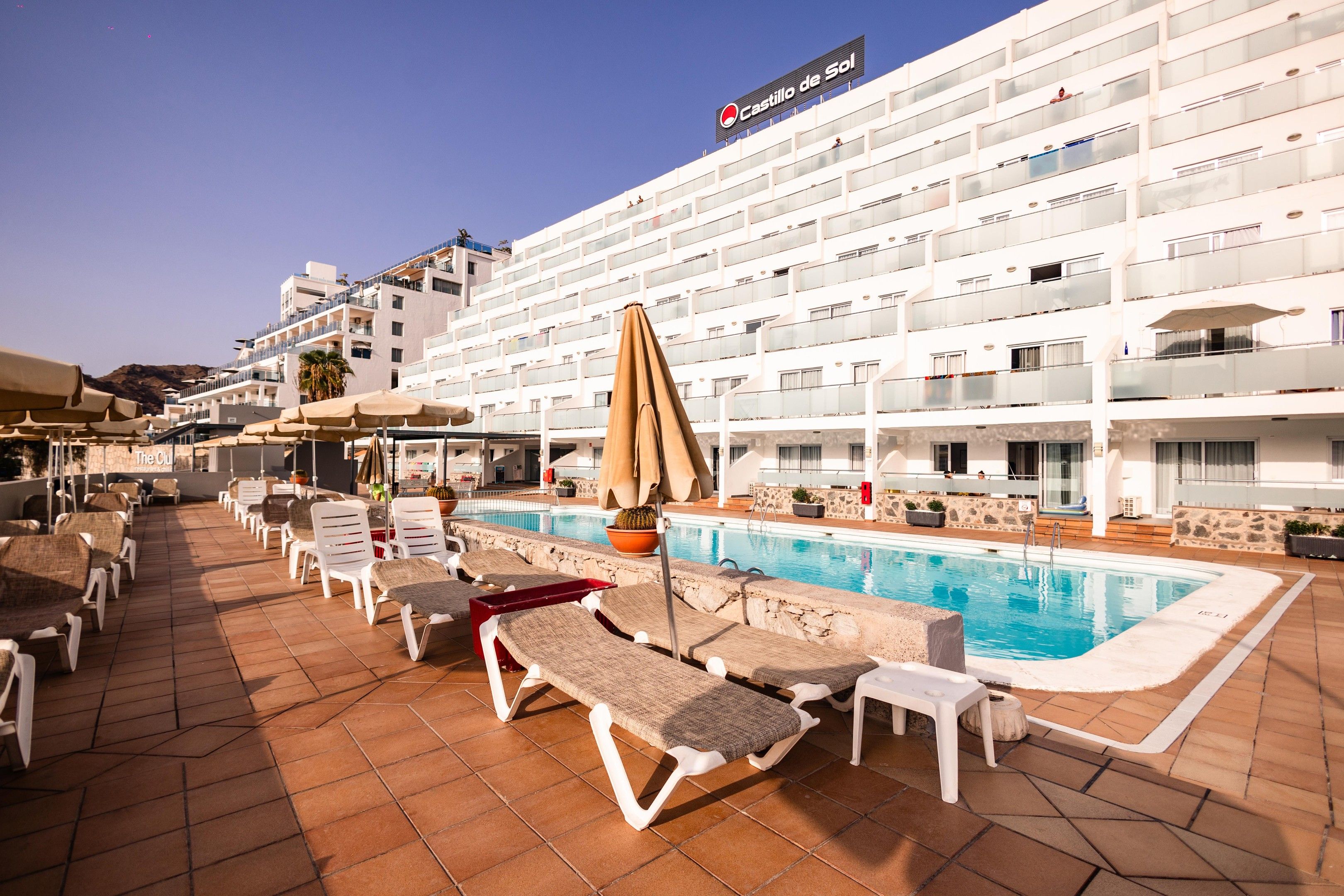 Un hotel con piscina, tumbonas y un cartel que dice 'Castillo de Sol'.