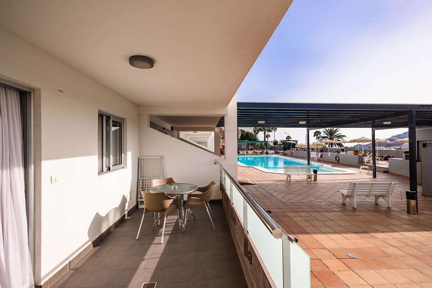 Un balcón con piscina, sillas y una mesa.