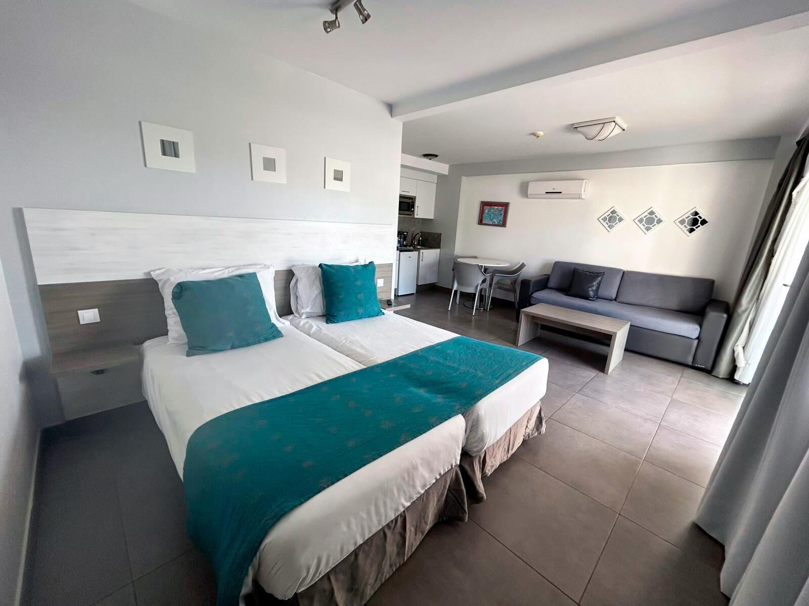 Une chambre d’hôtel comprenant un lit, un canapé, une petite table et une kitchenette.
