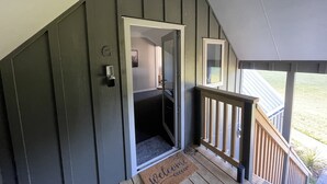 A wooden staircase leading to a dark green door with a mailbox and a doormat. - Pudding Hill Lodge & Chalets (Methven)